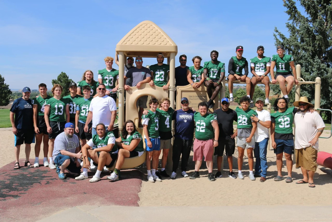 Senior football players pose in front of playground equipment