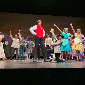 Gaston and ensemble sing on stage.