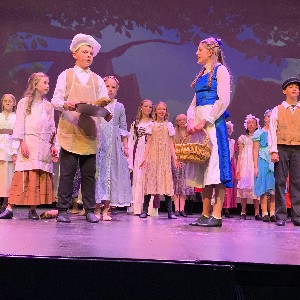 Belle and the baker talking on stage.