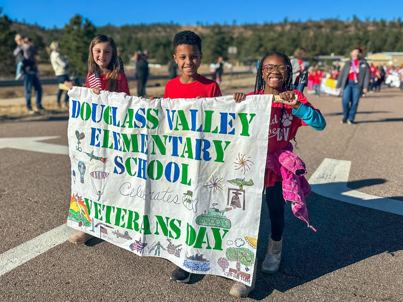 students holding a douglass valley sign in the veterans day parade