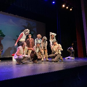 The lost boys huddling together on stage.