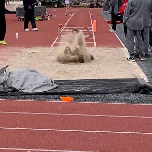 Long jumper kicks up sand while landing in the pit
