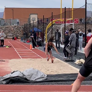 Student jumping into the long jump sand pit