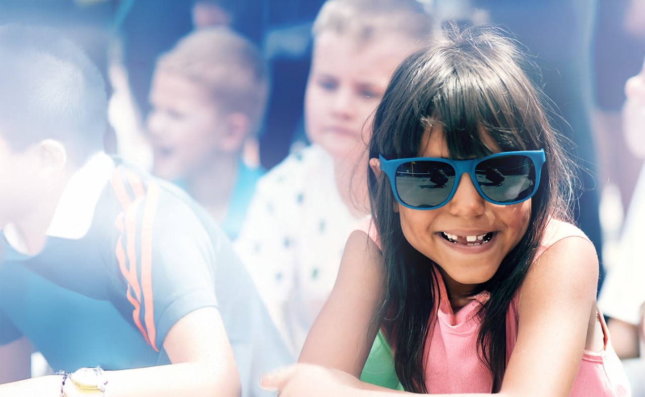 A young girl wears sunglasses at a school event.