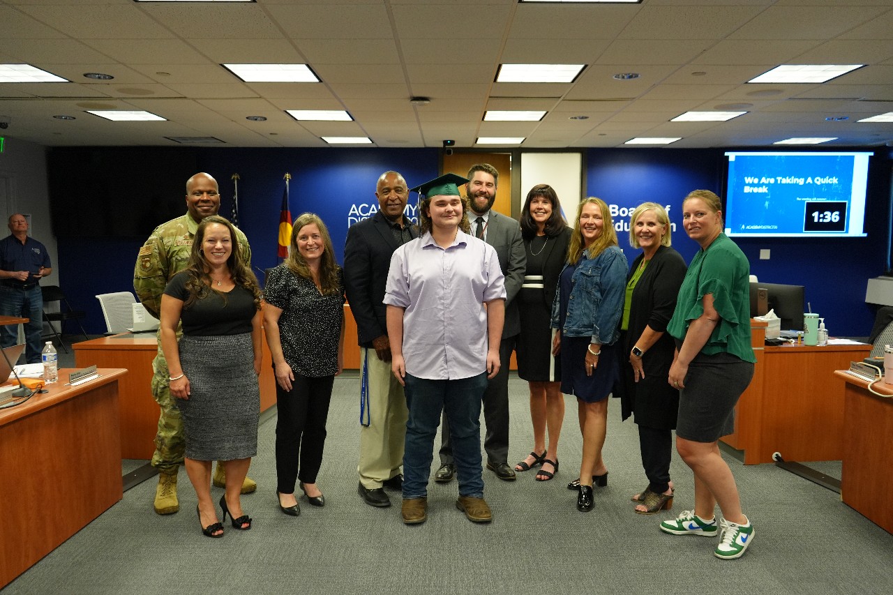 D20 Board of Education, Superintendent, Pine Creek Creek staff smile for a photo with a new Pine Creek graduate