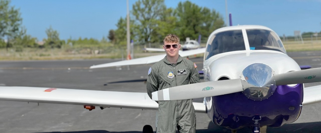 An AAHS student stands in front of a light aircraft.