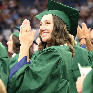 Girl looking up to the stands with a smile on graduation day