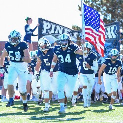 The team running out onto the field, carrying the American flag at the start of the game