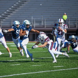 Player tries to avoid bein tackled while running the ball down the field