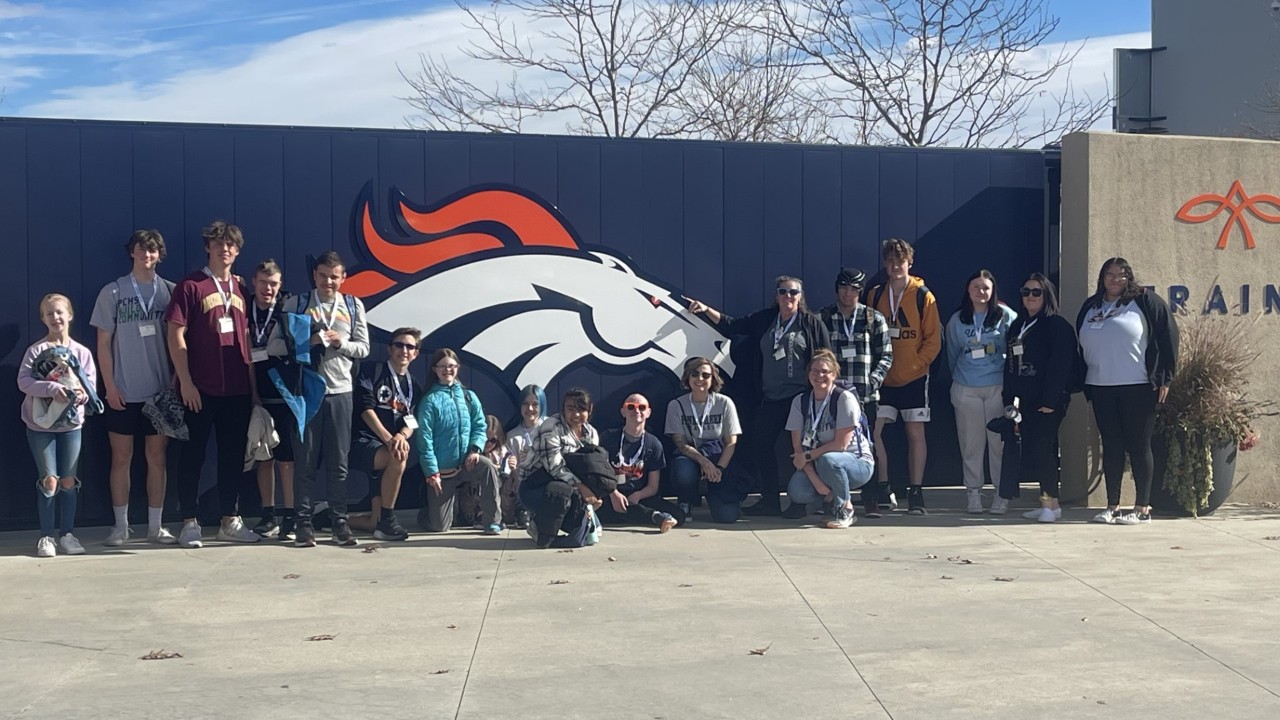 Group shot in front of Broncos logo