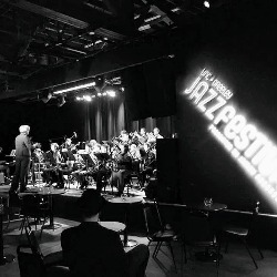 A black and white image of the PCHS Jazz Band playing in front of customer tables.