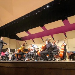 Orchestra students perform on stage.