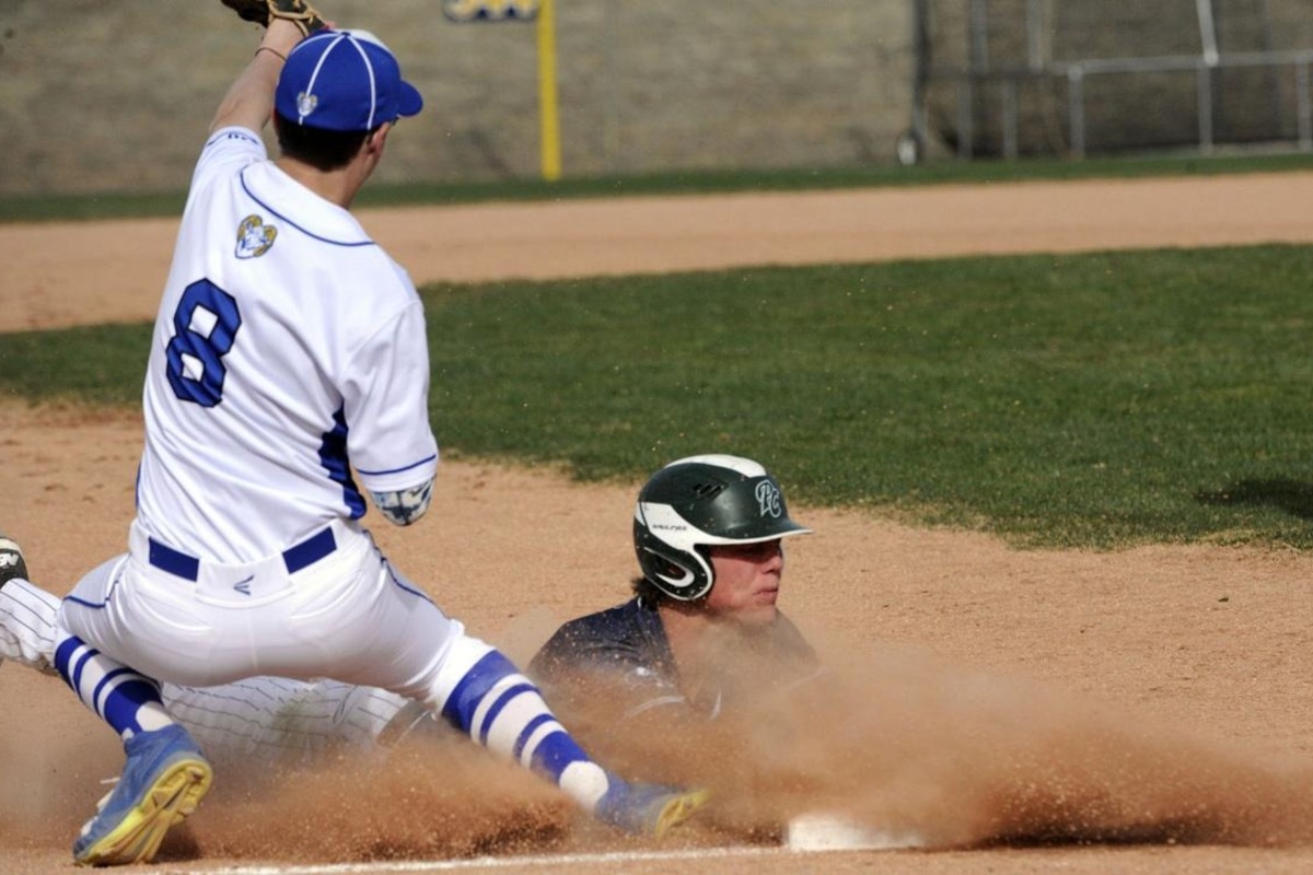 An RHS baseball player catches a ball as his opponent slides into base.
