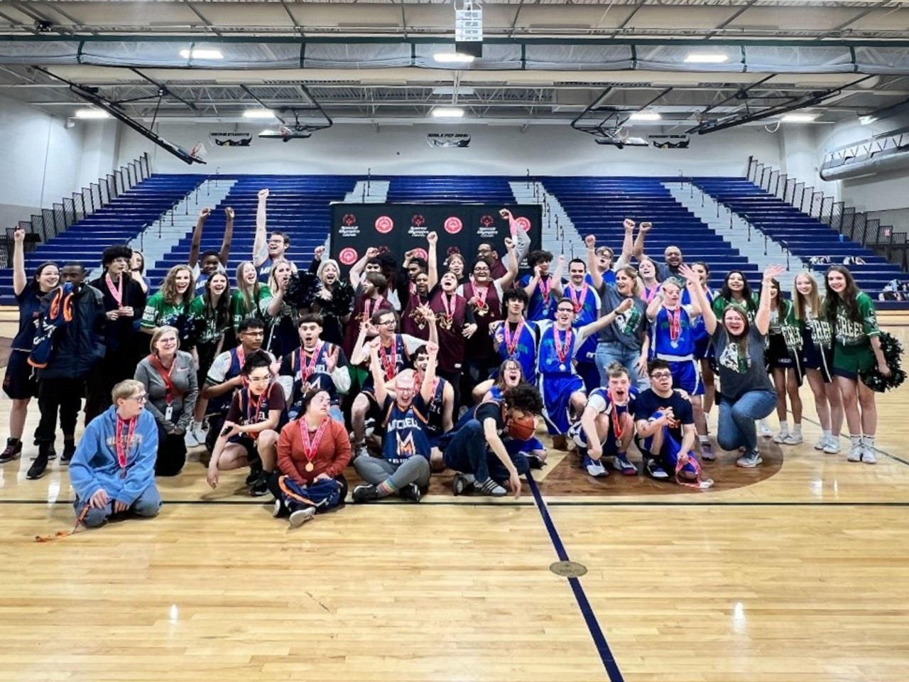 a large group of players and fans posing after a game wearing medals