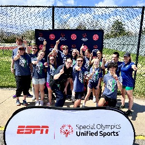 A group team photo next to an ESPN - Special Olympics sponsor sign.