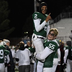 Player #55 holding up his teammate in celebration of winning the game.