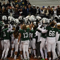 Players hold their helmets in the air in celebration of the win