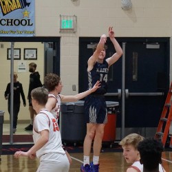 An AAHS basketball player shoots a ball at the hoop.