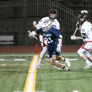 Boys lacrosse player runs the ball down the field