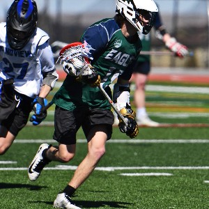 Boys lacrosse player running the ball down the field.