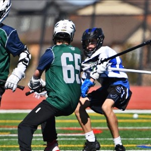 Boys lacrosse players reaching with their sticks to try to knock the ball away from the opponent.