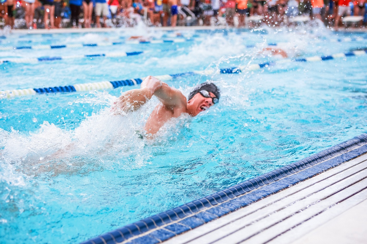 A high school swimmer races in a swim meet.