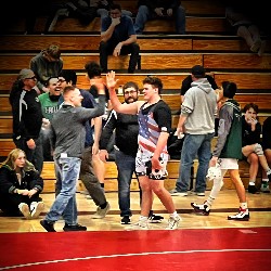 Wrestler high-fives supporter on the sideline after winning his match