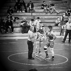 Referee holds Pine Creek wrestler's arm high, indicating he just won his competition