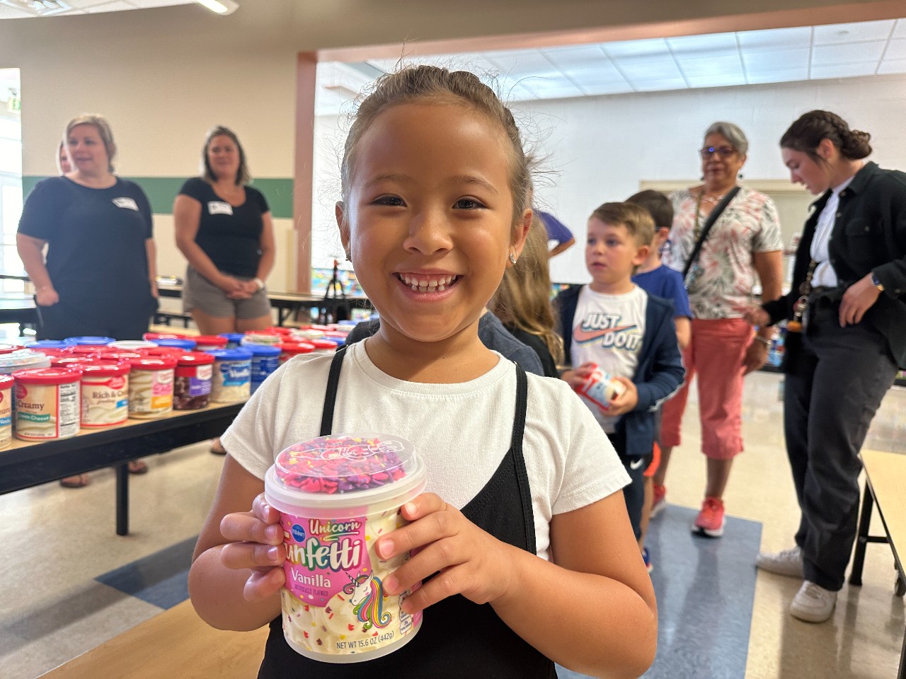 student smiles with a tub of frosting