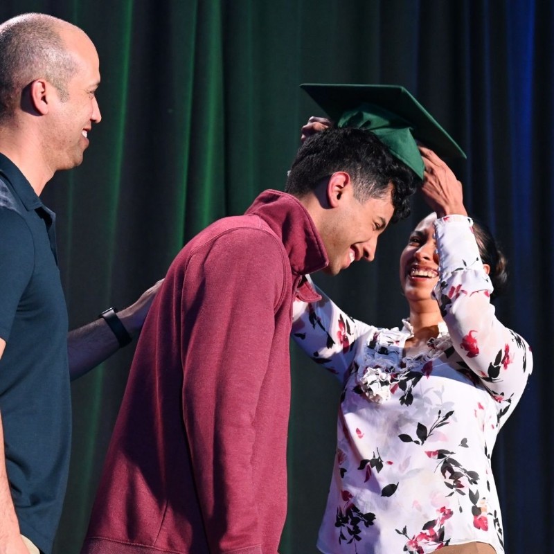 Family laughing while putting on Graduation cap