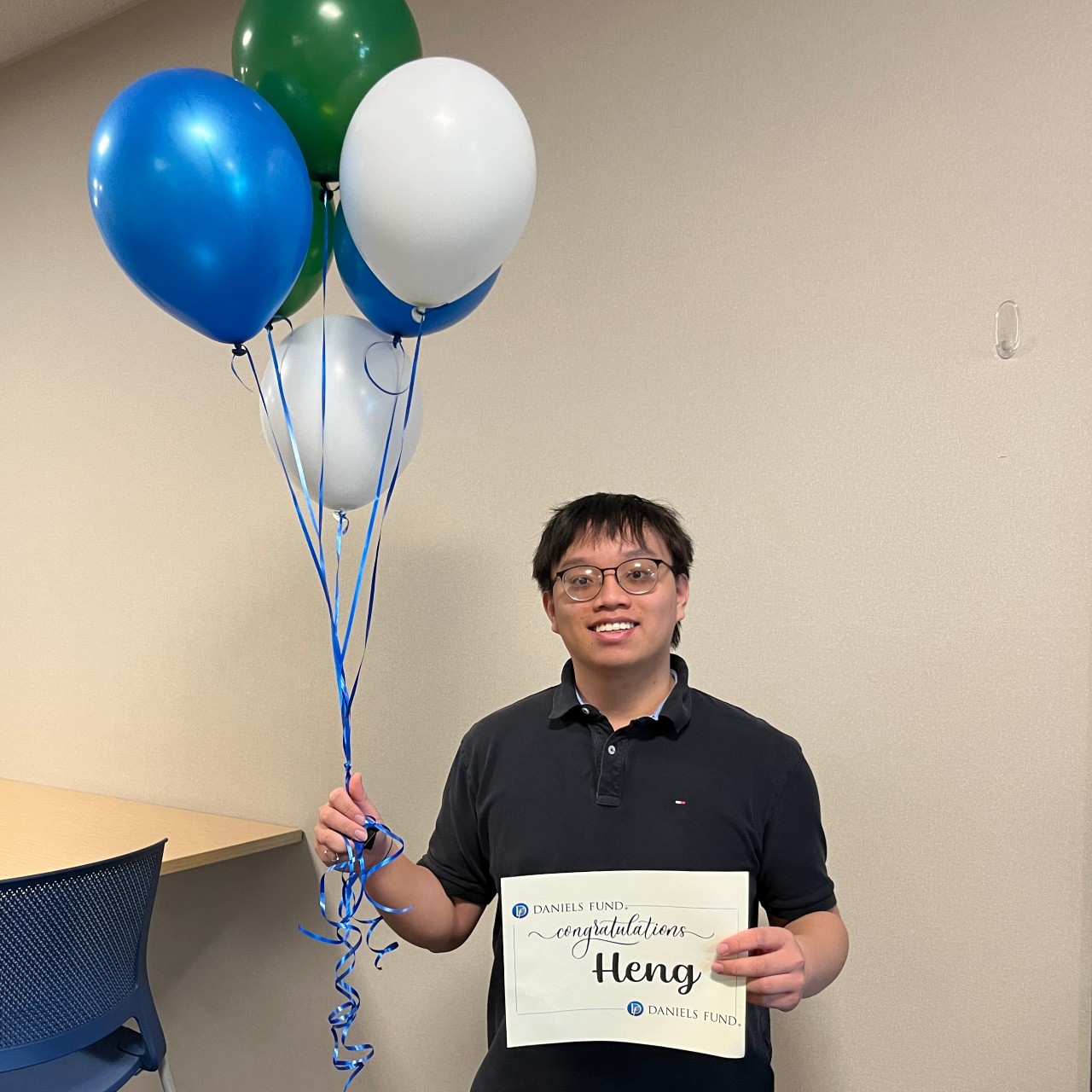 Student holding balloons and certificate