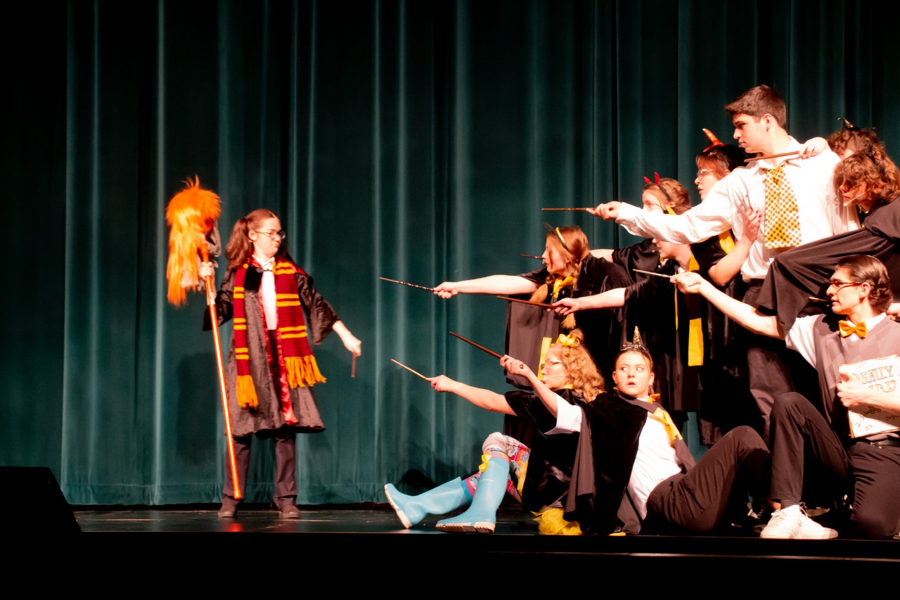 A group of students pointing wands at a single student