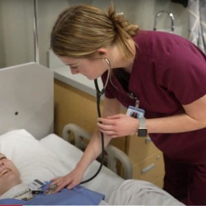 A student practices listening to the heartbeat on another student.