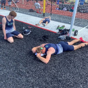 Students laying to the side of the track, resting and stretching