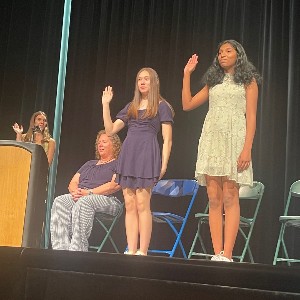 Two students holding up their hand to be inducted into Student lighting a battery-operated candle as part of the National Honor Society for Dance Arts 