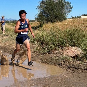 Boy running through mud puddle