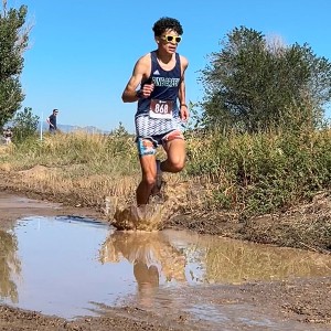 Boy running through mud puddle on the course