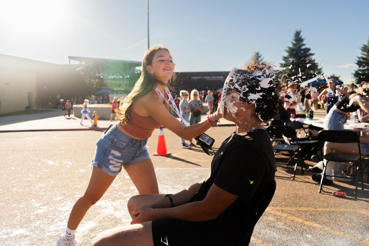 Liberty student thows a whip cream pie into another student's face at the Homecoming Tailgate celebration in front of Liberty High School.
