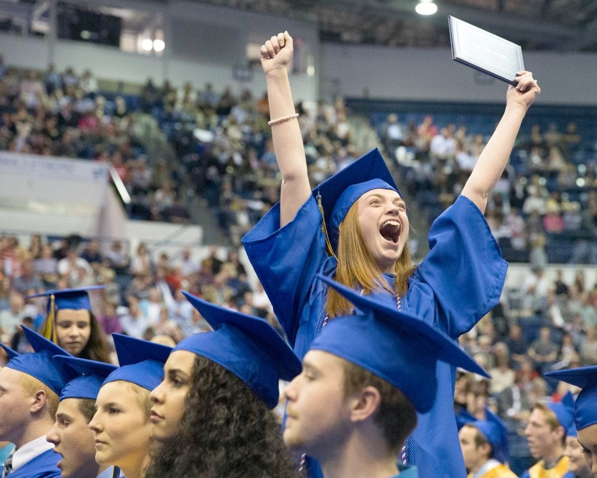 A Rampart High School student throws her arms in the air celebrating her graduation.