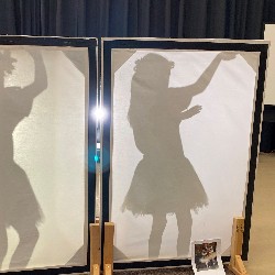 A silhouetted student dressed as a tropical dancer.