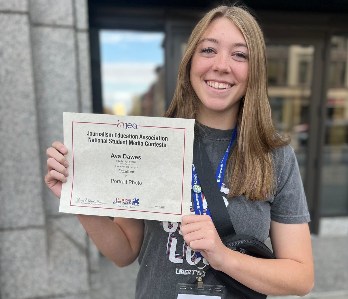 Liberty yearbook student Ava Dawes stands with a certificate from the Journalism Education Association National Student Media Contest for the Excellent Portrait Photo.