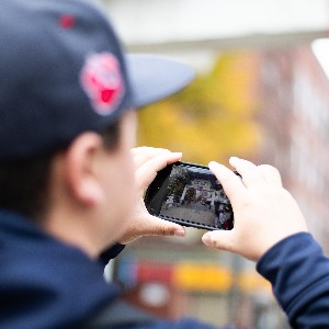 Liberty yearbook student takes a picture of the buildings and streets in Boston with his phone.
