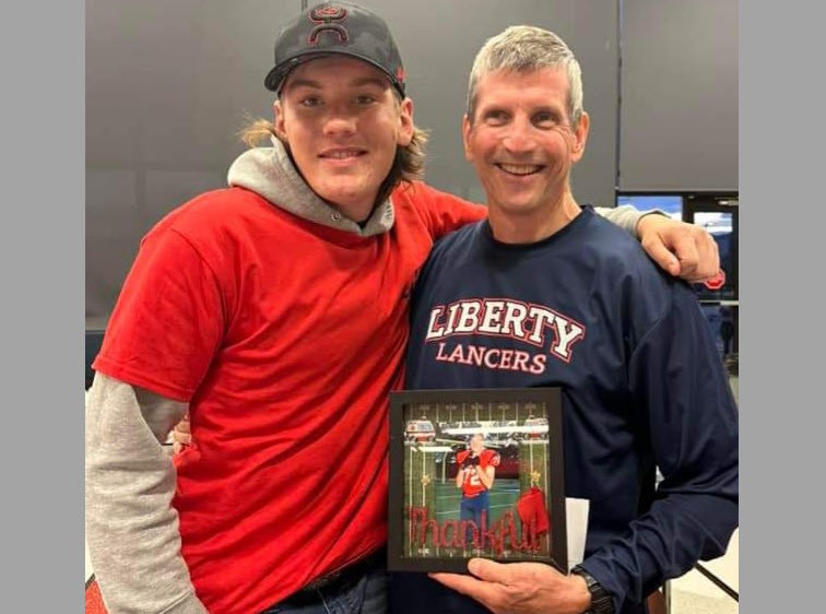 Liberty's athletic trainer P.J. Gardner holds a framed picture and stands arm in arm with Liberty student athlete Jordan O'Connell.