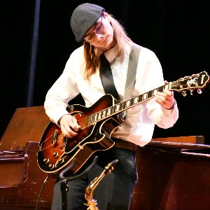 Student playing guitar and looking at the strings