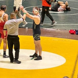 Referee holding up the arm of a Pine Creek wrestler who just won his match!