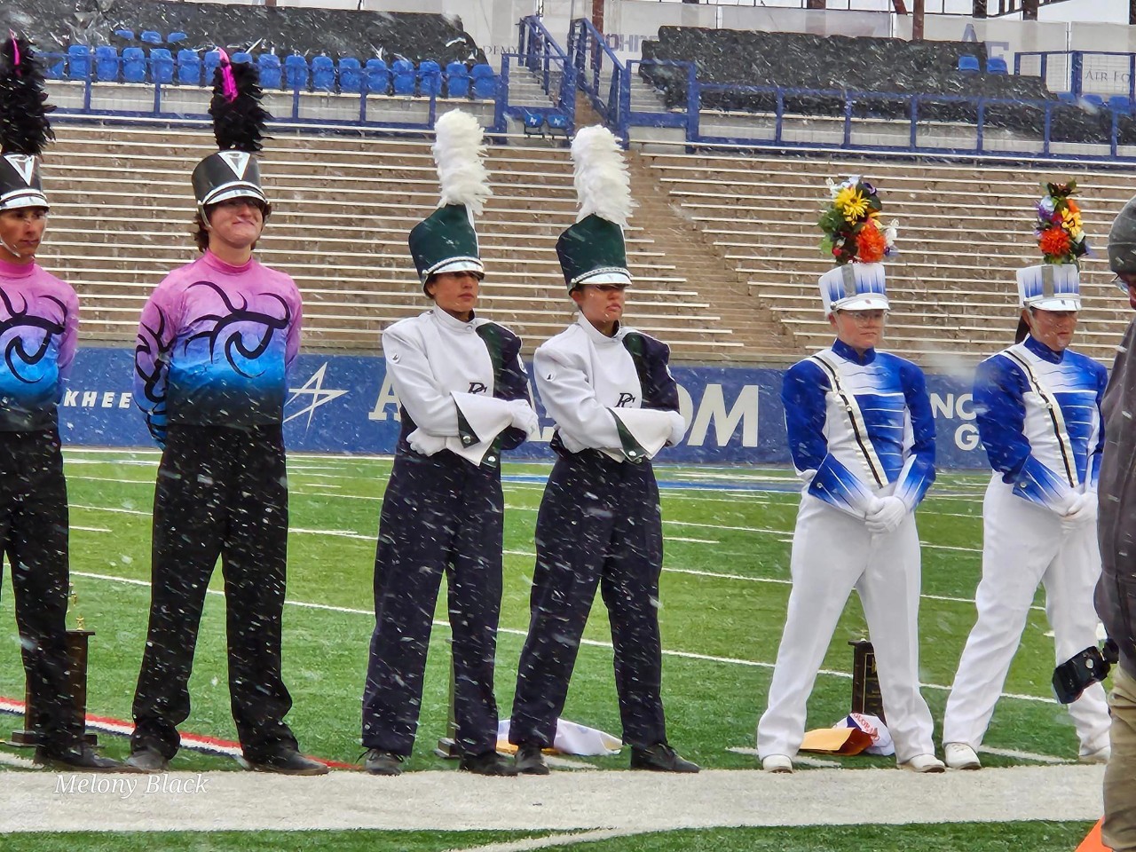 Drum majors from several bands, standing at attention  