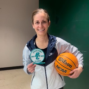 Coach Jubic holding a basketball and an award that says, "Coach Jubic 100th PC Win FFC 2/5/24"