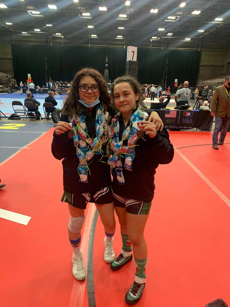 Two female wrestlers pose with medals at the State Championship