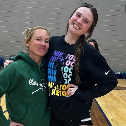 Student poses with PE teacher on the basketball court