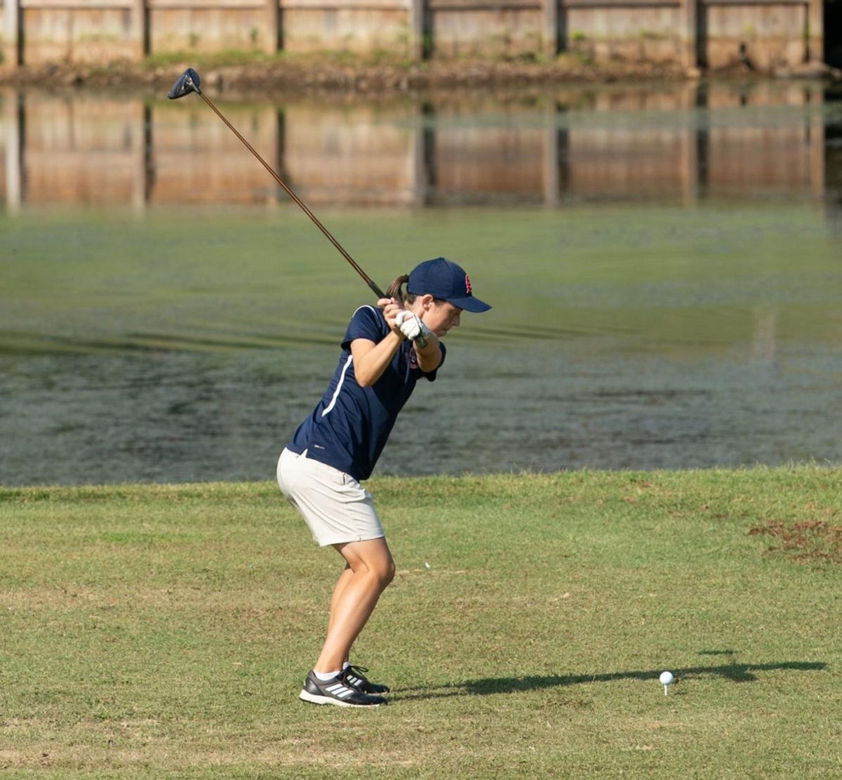 A golf team member lines up a ball on the golf course.